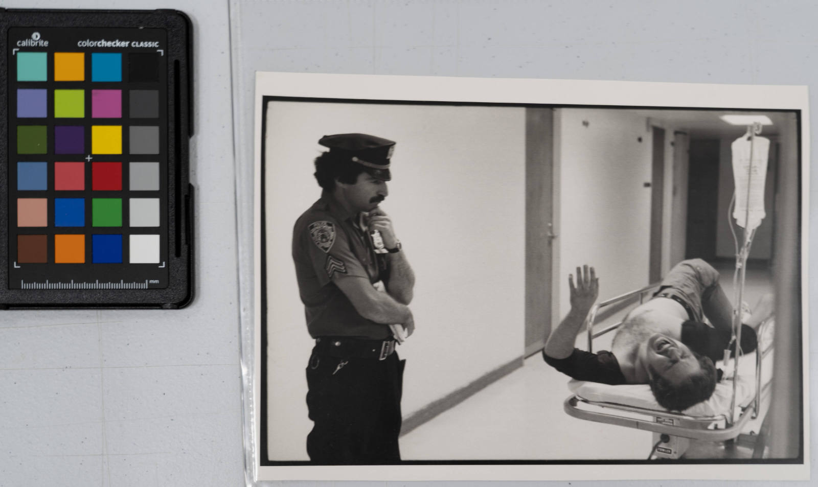 A police officer of the 9th precinct patiently waits in the hospital emergency ward for a victim, shot in the leg, to say what happened. The man said he knew nothing but the police found out afterwards he had visited a private social club and was shot in a dispute. Because his leg wound is not considered serious at the moment, the man is waiting in the hospital hallway to be operated on, Bellevue Hospital Emergency Ward, New York City