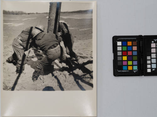 New York Telephone Company: "Line Gang"  - five technicians planting telephone pole in mud